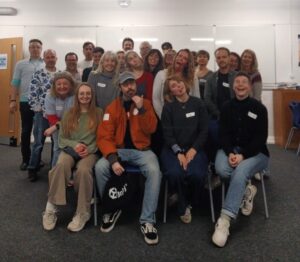 Large group of AndAlso improv students in their classroom smiling cherrily at the camera