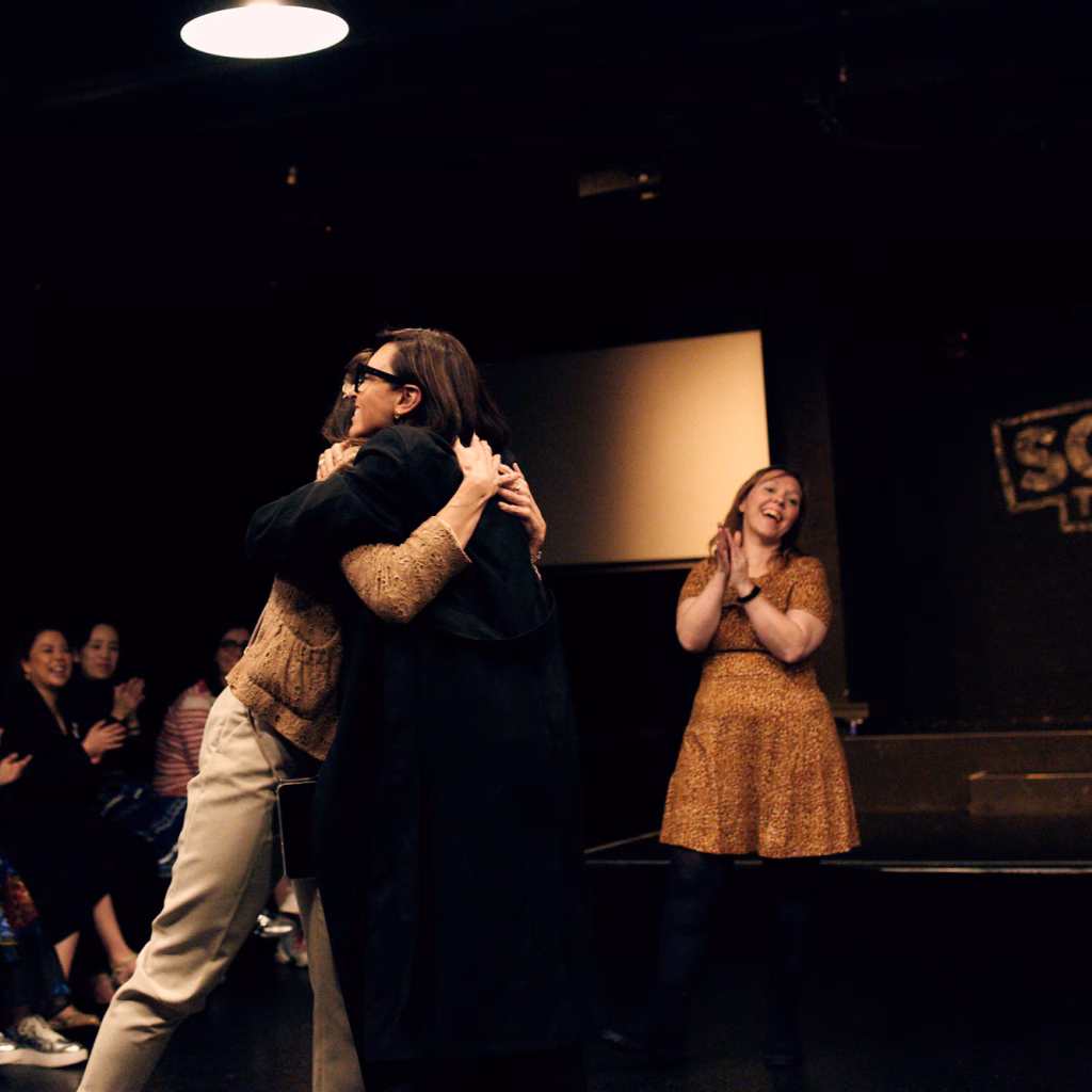 Improv students taking part in a class with Heather Urquhart teaching in the background.